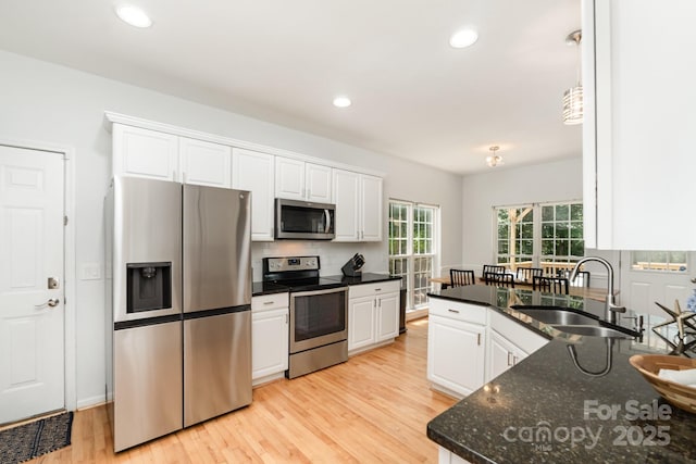 11624 Crossroads Pl, Concord, NC 28025 - kitchen with appliances with stainless steel finishes, white cabinets, light wood-style flooring, backsplash, and dark stone counters
