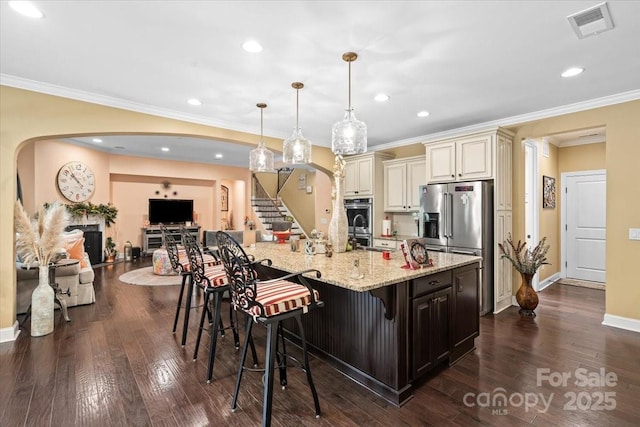 16402 Doves Canyon Ln, Charlotte, NC 28278 - kitchen featuring cream cabinetry, arched walkways, stainless steel appliances, light stone counters, and a kitchen bar