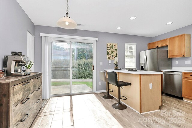 5980 Cougar Ln, Charlotte, NC 28269 - kitchen with appliances with stainless steel finishes, light wood-style floors, recessed lighting, a kitchen breakfast bar, and light countertops
