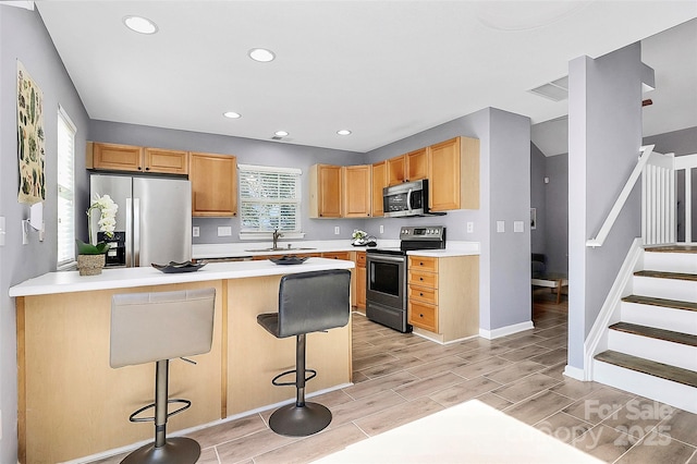 5980 Cougar Ln, Charlotte, NC 28269 - kitchen with stainless steel appliances, a breakfast bar area, a peninsula, recessed lighting, and light countertops