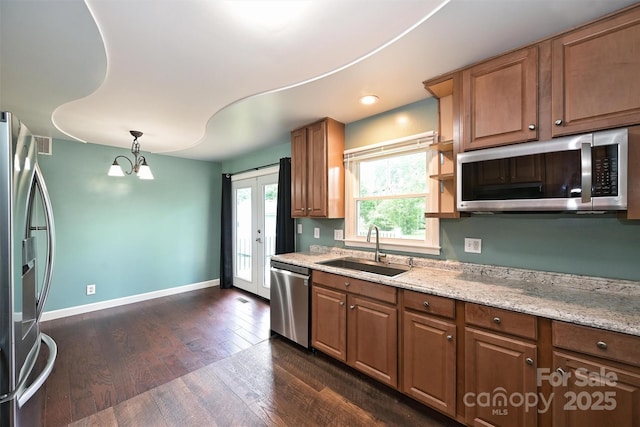 3729 Woodleaf Rd, Charlotte, NC 28205 - kitchen with stainless steel appliances, dark wood finished floors, light stone counters, pendant lighting, and brown cabinetry