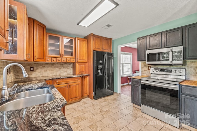 1276 Winding Path Rd, Clover, SC 29710 - kitchen featuring appliances with stainless steel finishes, backsplash, dark stone countertops, glass insert cabinets, and brown cabinets