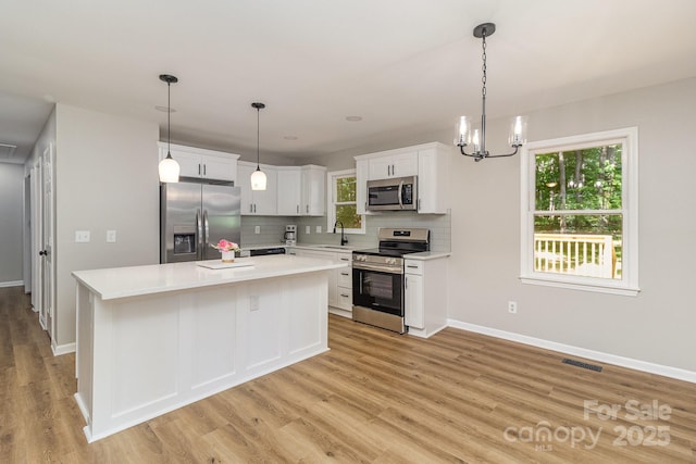 1118 Brookwood Dr, Stanley, NC 28164 - kitchen with appliances with stainless steel finishes, decorative backsplash, light countertops, white cabinets, and light wood-type flooring