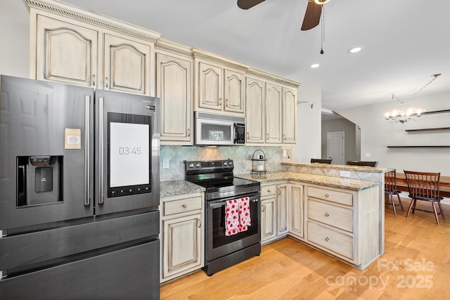 206 Taylor Cir, Granite Falls, NC 28630 - kitchen featuring stainless steel appliances, cream cabinetry, a peninsula, light wood-type flooring, and a ceiling fan