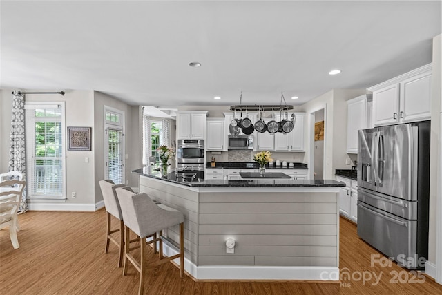 3020 Waxhaw Crossing Dr, Waxhaw, NC 28173 - kitchen featuring stainless steel appliances, light wood finished floors, white cabinets, a kitchen bar, and recessed lighting