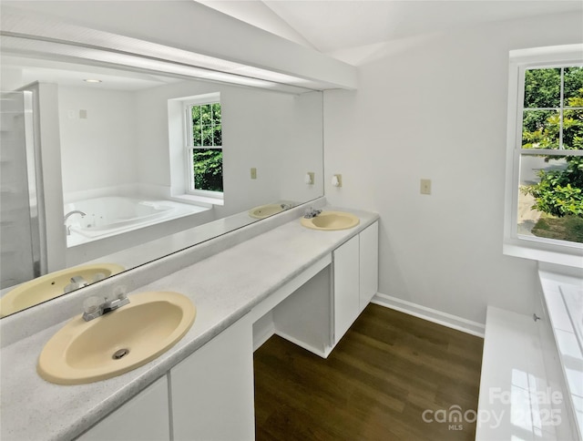 424 Mallard Dr, Pineville, NC 28134 - bathroom featuring wood finished floors, double vanity, a bath, and vaulted ceiling