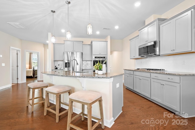 4116 Tory Path Rd, Waxhaw, NC 28173 - kitchen with appliances with stainless steel finishes, decorative backsplash, light stone counters, a kitchen island with sink, and a kitchen breakfast bar