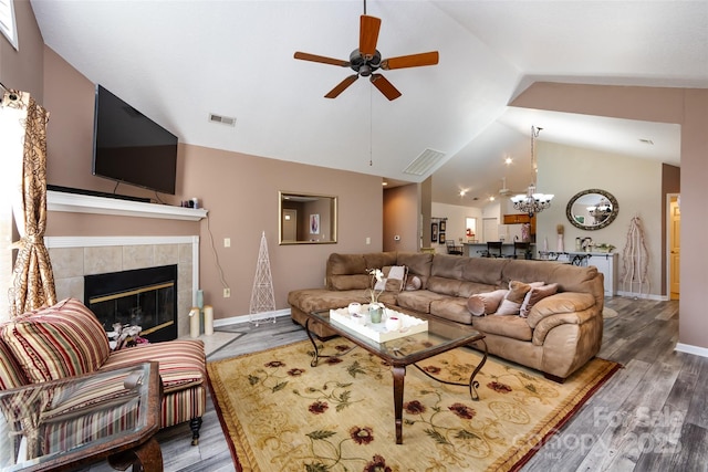 6811 Ledgestone Pl, Charlotte, NC 28227 - living room with lofted ceiling, a ceiling fan, wood finished floors, a tiled fireplace, and a chandelier