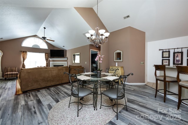 6811 Ledgestone Pl, Charlotte, NC 28227 - dining area with lofted ceiling, ceiling fan, wood finished floors, a fireplace, and a chandelier