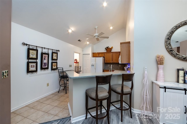 6811 Ledgestone Pl, Charlotte, NC 28227 - kitchen with white fridge with ice dispenser, brown cabinetry, tasteful backsplash, a peninsula, and light countertops