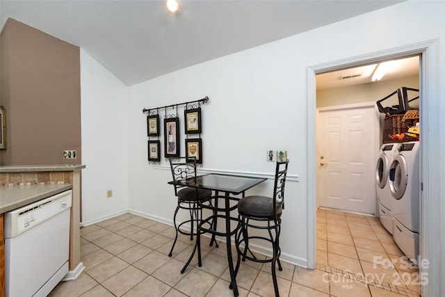 6811 Ledgestone Pl, Charlotte, NC 28227 - dining space featuring washing machine and dryer, light tile patterned flooring, and vaulted ceiling