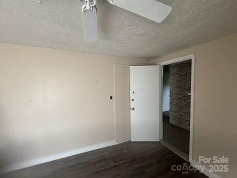 127 Hill St, Mooresboro, NC 28114 - empty room with a textured ceiling, dark wood-style flooring, and a ceiling fan