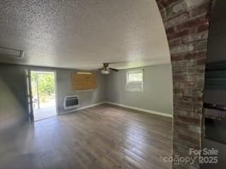 127 Hill St, Mooresboro, NC 28114 - unfurnished living room with ceiling fan, a textured ceiling, wood finished floors, and a wall mounted AC