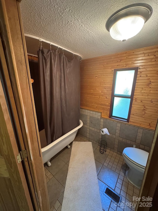 19 Timbers Edge Ln Unit 23, Fairview, NC 28730 - full bathroom featuring tile walls, a textured ceiling, tile patterned flooring, a wainscoted wall, and shower / tub combo with curtain