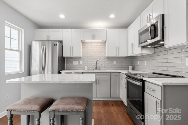 11023 Kinston Ridge Pl, Charlotte, NC 28273 - kitchen featuring appliances with stainless steel finishes, dark wood-type flooring, decorative backsplash, a kitchen bar, and recessed lighting