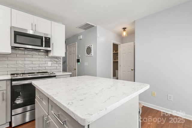 11023 Kinston Ridge Pl, Charlotte, NC 28273 - kitchen featuring stainless steel appliances, dark wood finished floors, a center island, backsplash, and white cabinetry