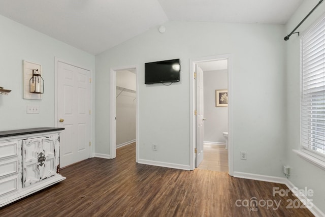 11023 Kinston Ridge Pl, Charlotte, NC 28273 - unfurnished bedroom with a walk in closet, dark wood-type flooring, lofted ceiling, multiple windows, and ensuite bathroom