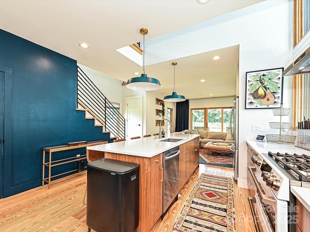 2553 Elkwood Cir, Charlotte, NC 28205 - kitchen featuring stainless steel appliances, open floor plan, light wood-type flooring, brown cabinets, and a kitchen island with sink