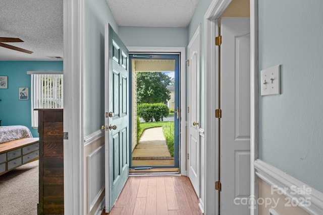 5221 Javitz Rd, Charlotte, NC 28216 - doorway featuring a textured ceiling, ceiling fan, healthy amount of natural light, wood finished floors, and a wainscoted wall