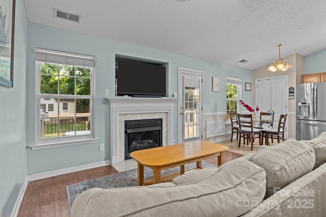 5221 Javitz Rd, Charlotte, NC 28216 - living area with a textured ceiling, healthy amount of natural light, a premium fireplace, a chandelier, and wood finished floors