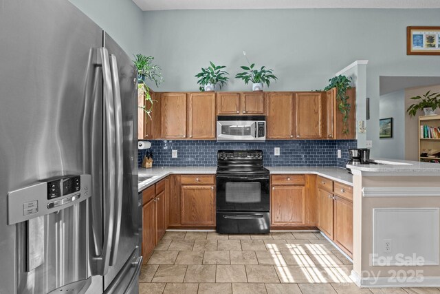 5221 Javitz Rd, Charlotte, NC 28216 - kitchen featuring stainless steel appliances, tasteful backsplash, light countertops, a peninsula, and brown cabinets