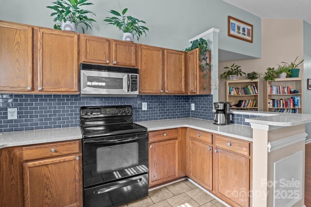 5221 Javitz Rd, Charlotte, NC 28216 - kitchen featuring stainless steel microwave, black range with electric stovetop, a peninsula, light countertops, and tasteful backsplash
