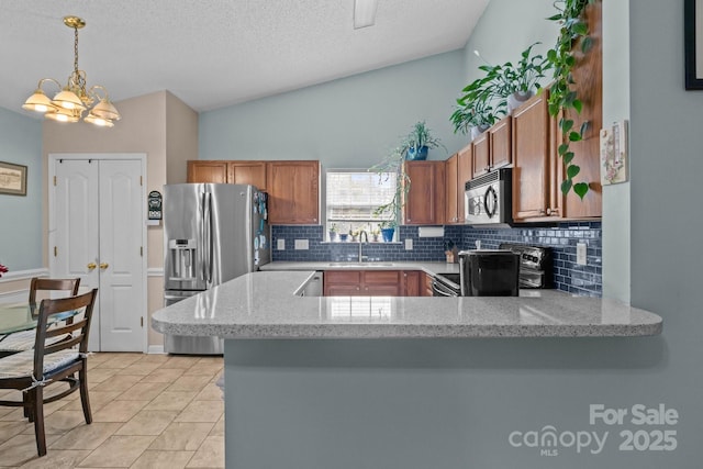 5221 Javitz Rd, Charlotte, NC 28216 - kitchen with stainless steel appliances, backsplash, brown cabinets, a peninsula, and decorative light fixtures