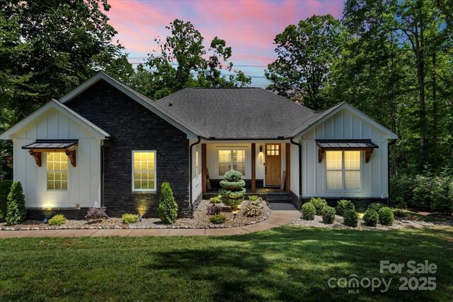 402 Wildlife Rd, Troutman, NC 28166 - modern farmhouse featuring board and batten siding, stone siding, a front yard, and a porch