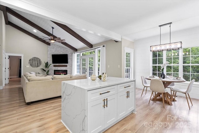 402 Wildlife Rd, Troutman, NC 28166 - kitchen with a large fireplace, white cabinets, light wood-style flooring, light stone countertops, and decorative light fixtures