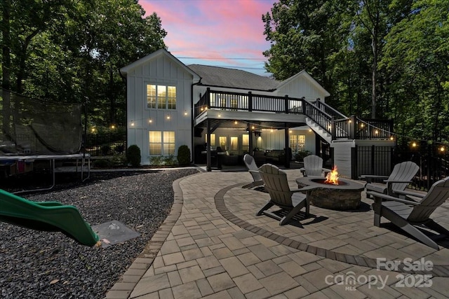 402 Wildlife Rd, Troutman, NC 28166 - back of property featuring a fire pit, board and batten siding, a trampoline, a patio area, and stairs