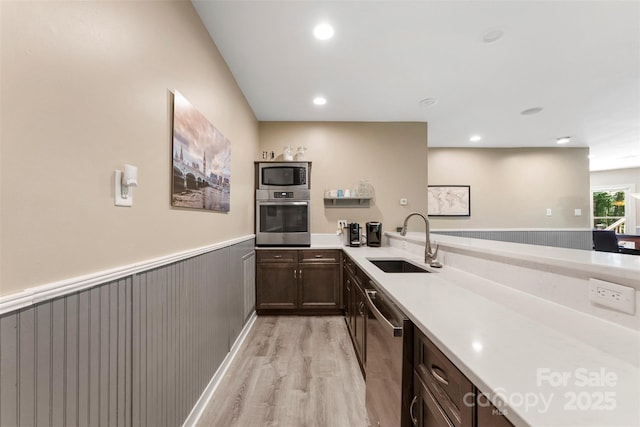10007 Hillspring Dr, Huntersville, NC 28078 - kitchen with appliances with stainless steel finishes, light wood finished floors, light countertops, a wainscoted wall, and dark brown cabinetry