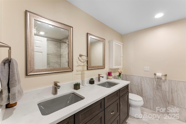 10007 Hillspring Dr, Huntersville, NC 28078 - bathroom featuring double vanity, a shower, tile walls, wainscoting, and recessed lighting