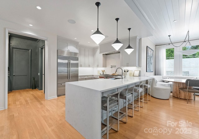 2837 Kenwood Sharon Ln, Charlotte, NC 28211 - kitchen with stainless steel built in refrigerator, a peninsula, a kitchen bar, light countertops, and light wood finished floors