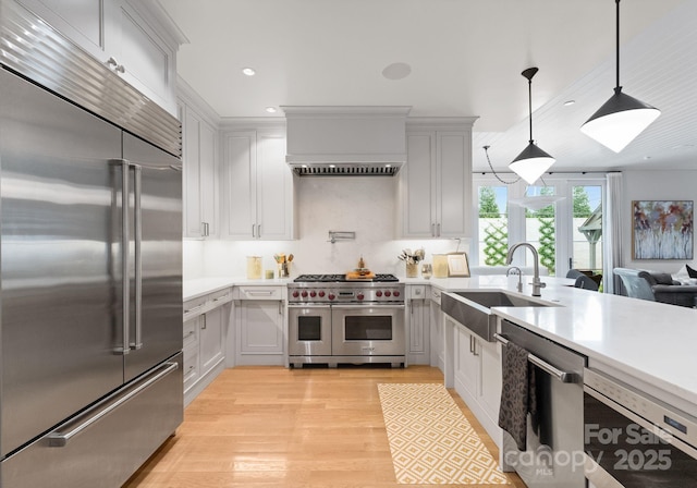 2837 Kenwood Sharon Ln, Charlotte, NC 28211 - kitchen with high quality appliances, light countertops, light wood-style floors, white cabinetry, and decorative light fixtures