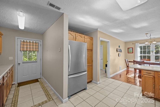 73 Waters Rd, Asheville, NC 28805 - kitchen featuring freestanding refrigerator, plenty of natural light, light tile patterned floors, a textured ceiling, and light countertops