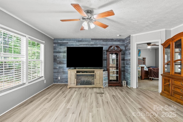 27 Sage Way, Clyde, NC 28721 - unfurnished living room with a ceiling fan, an accent wall, wood finished floors, crown molding, and a textured ceiling