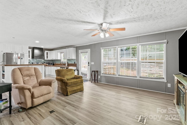 27 Sage Way, Clyde, NC 28721 - living room with ceiling fan, light wood-style floors, a textured ceiling, recessed lighting, and crown molding