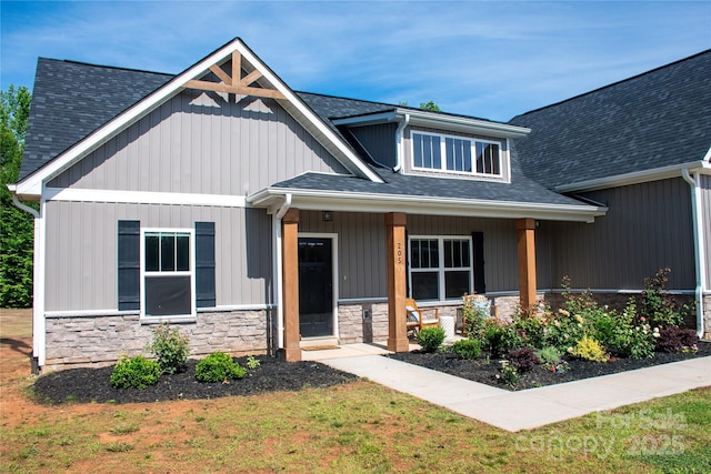 205 Spring Creek Dr, Mount Holly, NC 28120 - craftsman-style home with stone siding, a front yard, a porch, and roof with shingles