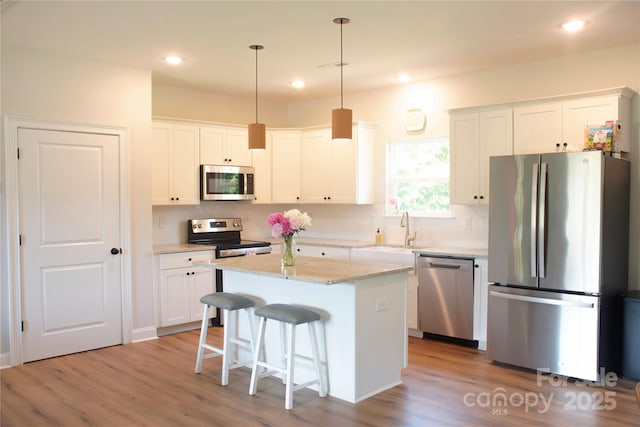 205 Spring Creek Dr, Mount Holly, NC 28120 - kitchen featuring appliances with stainless steel finishes, backsplash, a kitchen island, white cabinetry, and recessed lighting