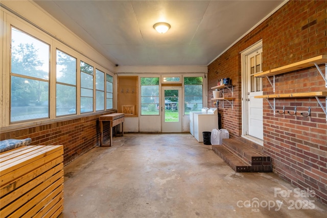 1132 Arbor Dr, Salisbury, NC 28144 - unfurnished sunroom with washer and clothes dryer, brick wall, unfinished concrete flooring, and plenty of natural light