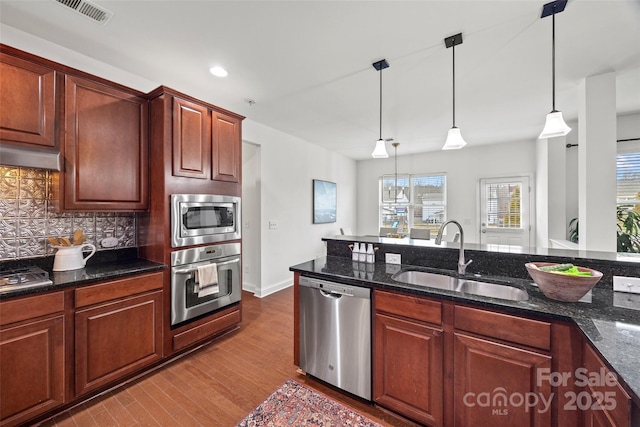 8312 Compton Acres Ln, Waxhaw, NC 28173 - kitchen with stainless steel appliances, tasteful backsplash, wood finished floors, hanging light fixtures, and recessed lighting