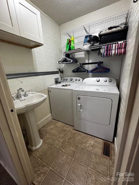 3375 Shepherd Rd, Maiden, NC 28650 - laundry room with washing machine and dryer, cabinet space, a textured ceiling, and dark tile patterned flooring