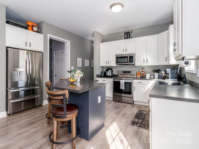 4652 Rocky Hollow Rd 4658, 4654, Davidson, NC 28036 - kitchen featuring appliances with stainless steel finishes, dark countertops, a center island, white cabinets, and light wood-style flooring