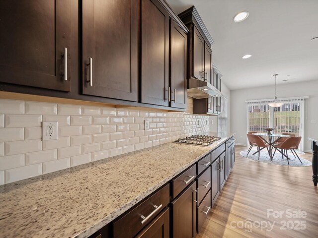 9582 Creighton Rd NW, Concord, NC 28027 - kitchen with dark brown cabinets, stainless steel gas stovetop, light stone countertops, light wood-style flooring, and recessed lighting