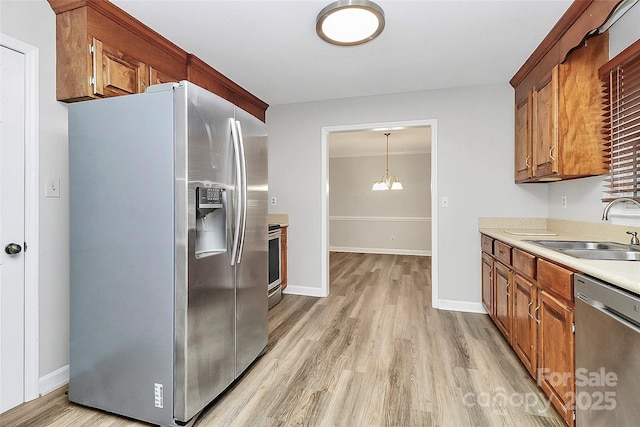 16509 Kimbolten Dr, Huntersville, NC 28078 - kitchen featuring stainless steel appliances, light wood-style floors, light countertops, brown cabinets, and a chandelier