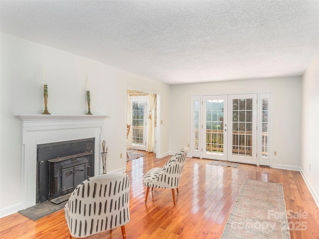 80 Gobblers Knob Dr, Clyde, NC 28721 - living room featuring light wood-style flooring, a fireplace with raised hearth, a textured ceiling, and french doors