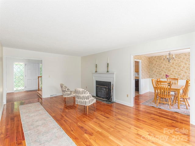 80 Gobblers Knob Dr, Clyde, NC 28721 - living area featuring a fireplace with flush hearth, light wood-type flooring, a chandelier, and wallpapered walls