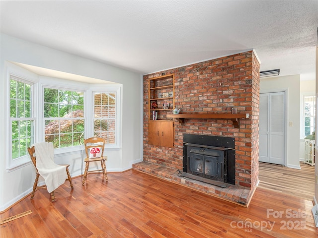80 Gobblers Knob Dr, Clyde, NC 28721 - living area featuring wood finished floors, a textured ceiling, a fireplace, and built in shelves