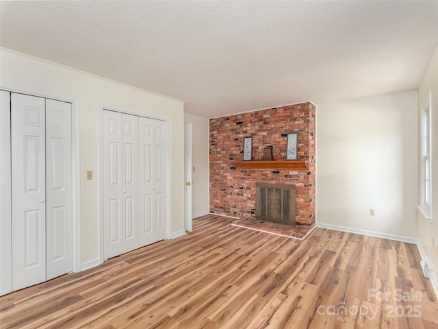 80 Gobblers Knob Dr, Clyde, NC 28721 - unfurnished living room featuring light wood-style flooring, a textured ceiling, and a brick fireplace