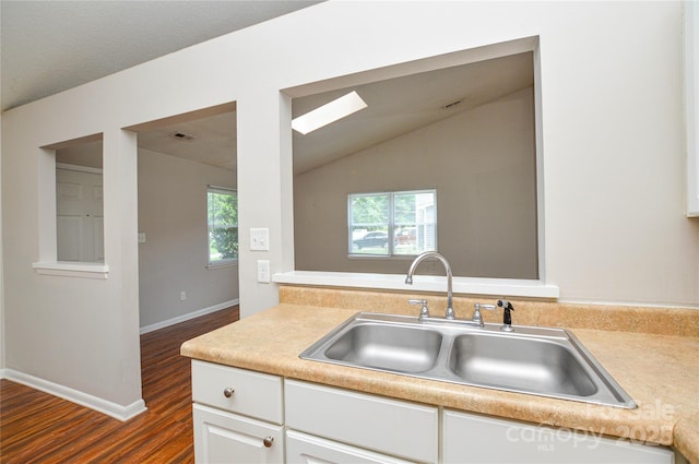 5424 Amado St, Charlotte, NC 28215 - kitchen with dark wood-type flooring, light countertops, lofted ceiling, and white cabinetry